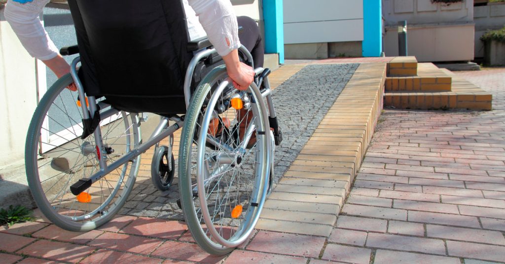 mulher na cadeira de rodas subindo uma rampa exemplificando a importância da acessibilidade na construção civil