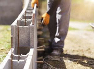 trabalhador na obra levantando muro de blocos com o melhor material a partir das dicas de construção