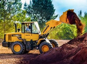 pá carregadeira de rodas komatsu amarela descarregando terra em um monte em ambiente aberto